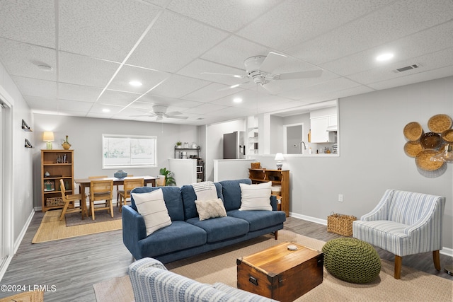 living room with sink, a paneled ceiling, ceiling fan, and light wood-type flooring