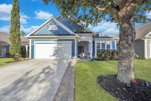 view of front of house with a standing seam roof, metal roof, a garage, driveway, and a front lawn