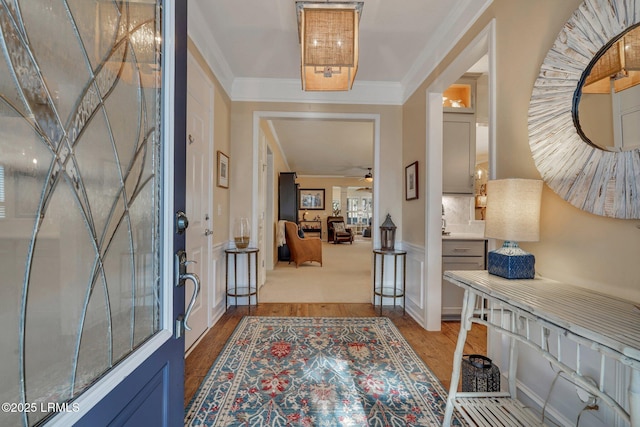 foyer with a ceiling fan, crown molding, and wood finished floors