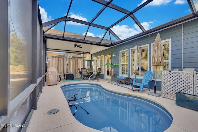 pool with a patio area, glass enclosure, and a ceiling fan