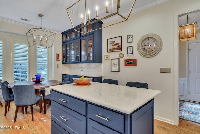 kitchen with crown molding, light countertops, visible vents, light wood-style floors, and blue cabinets