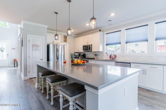 kitchen with white cabinetry, a breakfast bar area, hanging light fixtures, a center island, and stainless steel appliances