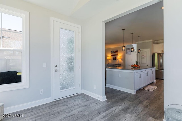 kitchen with pendant lighting, white cabinetry, plenty of natural light, and stainless steel fridge