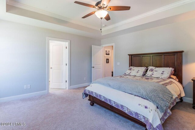 carpeted bedroom featuring ornamental molding, ceiling fan, and a tray ceiling