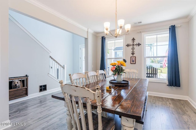 dining area featuring wood-type flooring, ornamental molding, and an inviting chandelier