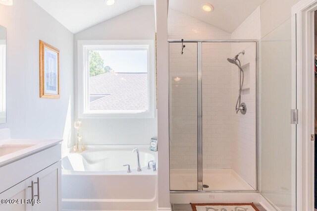 bathroom featuring vanity, separate shower and tub, and vaulted ceiling