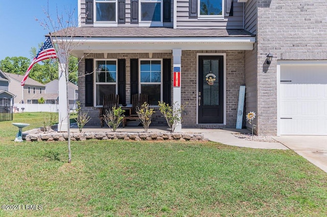 entrance to property featuring a garage, covered porch, and a lawn