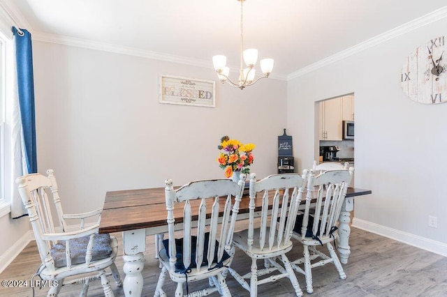 dining room featuring ornamental molding, a chandelier, and light hardwood / wood-style flooring