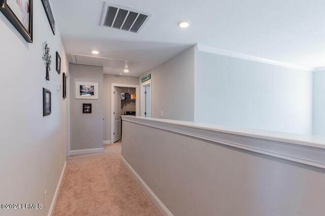 hall with ornamental molding and light carpet