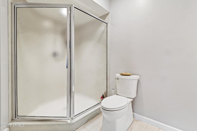 bathroom with tile patterned flooring, a shower stall, toilet, and baseboards