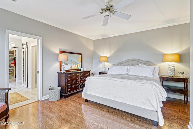 bedroom featuring ceiling fan, crown molding, baseboards, and wood finished floors