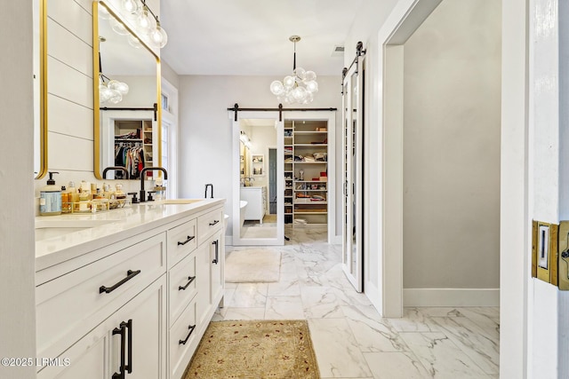 full bathroom with a walk in closet, marble finish floor, double vanity, a sink, and baseboards