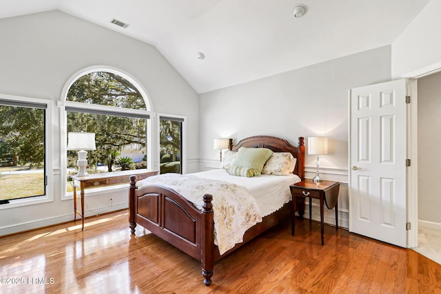 bedroom with lofted ceiling, visible vents, and wood finished floors