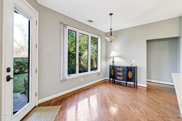 dining space with a wealth of natural light, wood-type flooring, visible vents, and baseboards