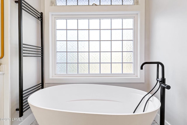 full bath featuring a freestanding tub and baseboards