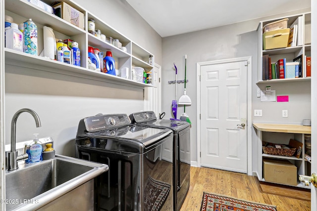 clothes washing area featuring laundry area, light wood-style flooring, washer and clothes dryer, and a sink