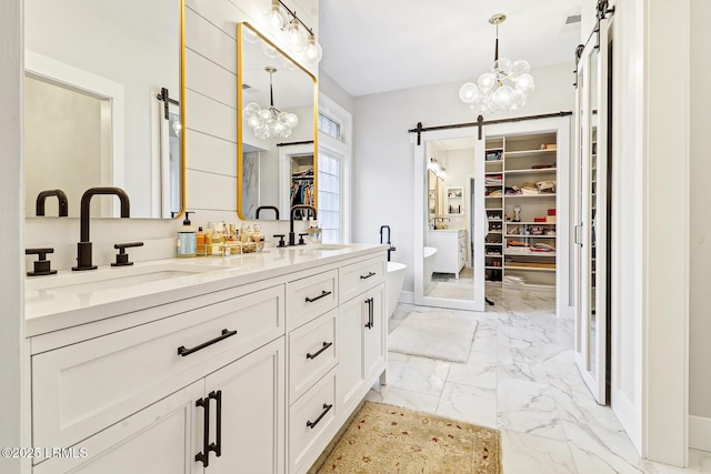 bathroom with marble finish floor, a sink, a spacious closet, and double vanity