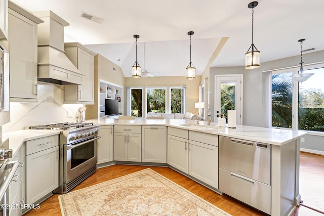 kitchen with stainless steel stove, light countertops, custom range hood, visible vents, and a sink