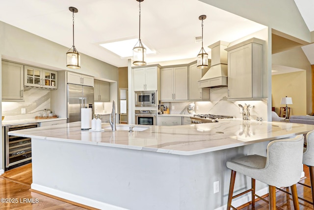 kitchen featuring built in appliances, wine cooler, a sink, light wood-style floors, and custom range hood