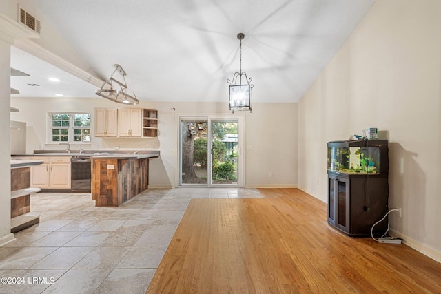 kitchen featuring pendant lighting, lofted ceiling, plenty of natural light, and black dishwasher