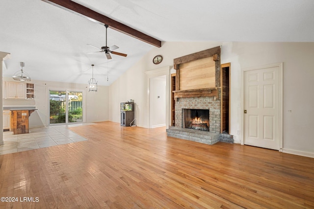 unfurnished living room with light hardwood / wood-style flooring, vaulted ceiling with beams, ceiling fan with notable chandelier, and a fireplace