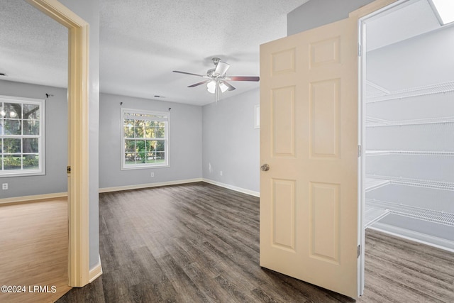 unfurnished room with a textured ceiling, dark hardwood / wood-style floors, and ceiling fan