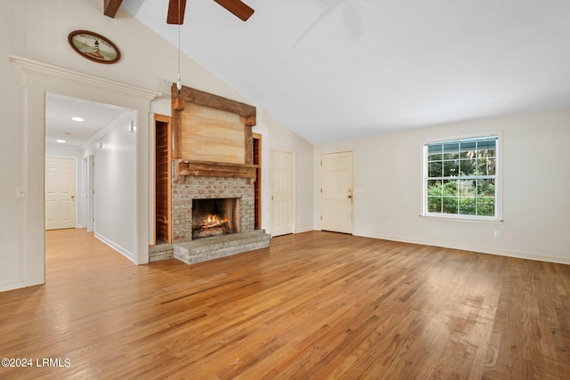 unfurnished living room featuring a fireplace, lofted ceiling with beams, ceiling fan, and light wood-type flooring