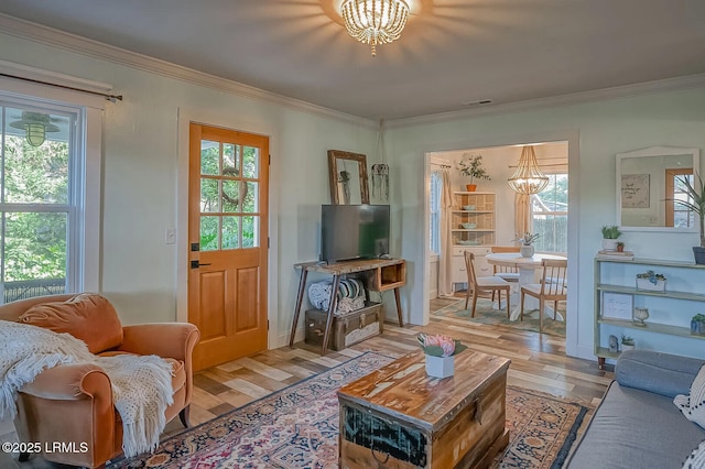 living room with plenty of natural light, an inviting chandelier, ornamental molding, and light wood finished floors