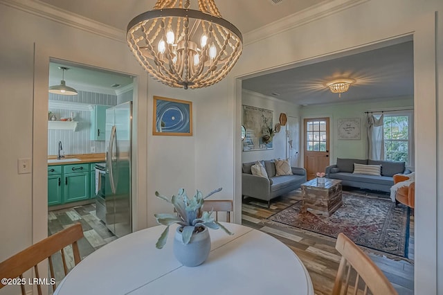 dining space with crown molding, a notable chandelier, and wood finished floors