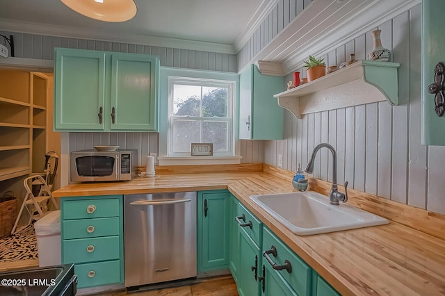 kitchen with ornamental molding, a sink, stainless steel appliances, green cabinets, and butcher block counters