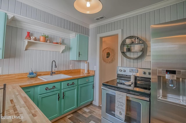 kitchen with visible vents, wooden counters, ornamental molding, a sink, and appliances with stainless steel finishes