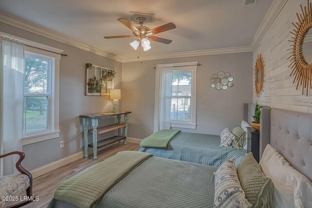 bedroom featuring a ceiling fan, visible vents, wood finished floors, baseboards, and ornamental molding