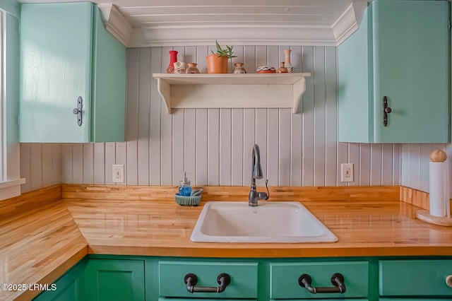 kitchen featuring green cabinets, wooden counters, and a sink