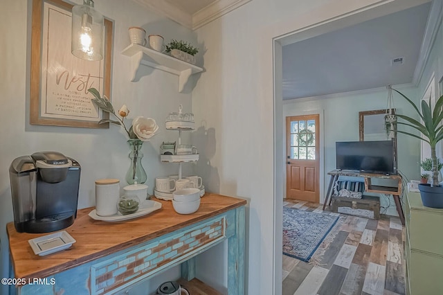 interior space with wood finished floors, visible vents, and ornamental molding