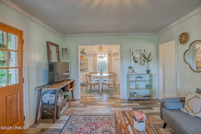 living area featuring crown molding, wood finished floors, visible vents, and baseboards