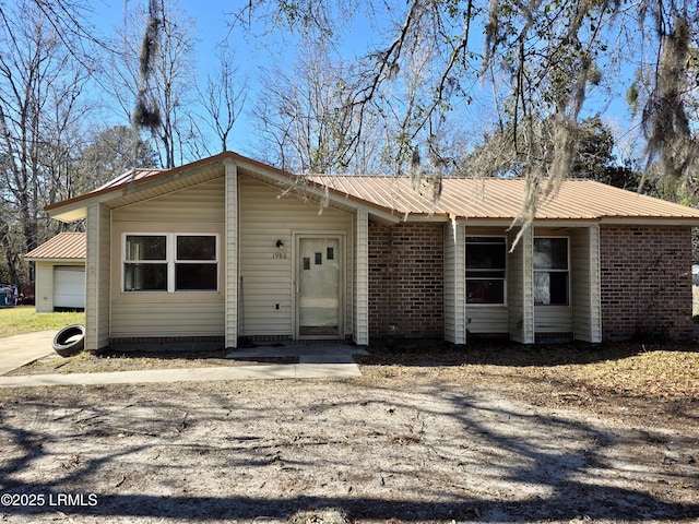 single story home featuring metal roof and brick siding