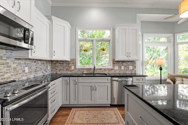 kitchen with appliances with stainless steel finishes, sink, white cabinets, and dark stone counters