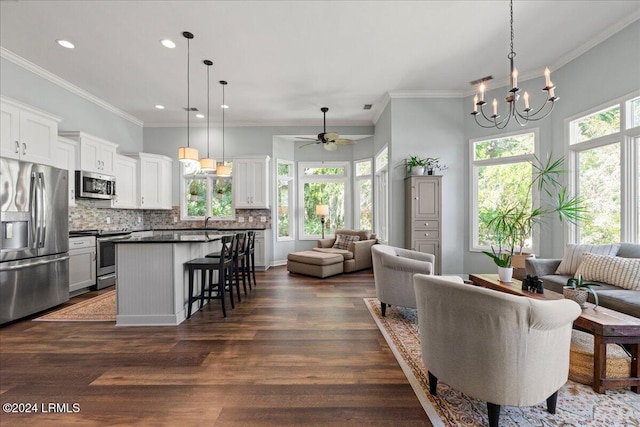 living room with sink, ceiling fan with notable chandelier, dark wood-type flooring, and ornamental molding