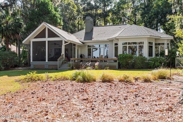 rear view of house with a sunroom, ceiling fan, and a lawn