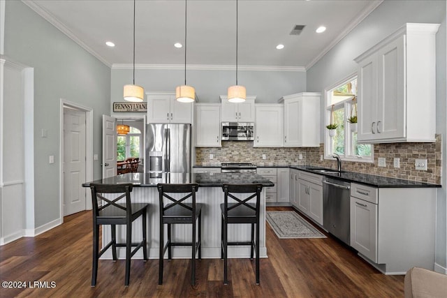 kitchen featuring appliances with stainless steel finishes, a kitchen island, pendant lighting, decorative backsplash, and white cabinets