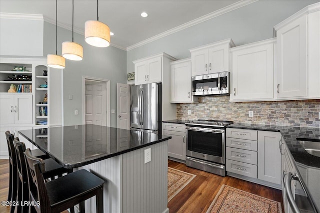 kitchen featuring white cabinetry, dark stone countertops, a kitchen breakfast bar, pendant lighting, and stainless steel appliances