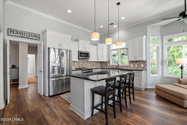 kitchen featuring white cabinetry, crown molding, a center island, hanging light fixtures, and stainless steel appliances