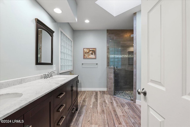 bathroom featuring vanity, hardwood / wood-style floors, a skylight, and a shower with door