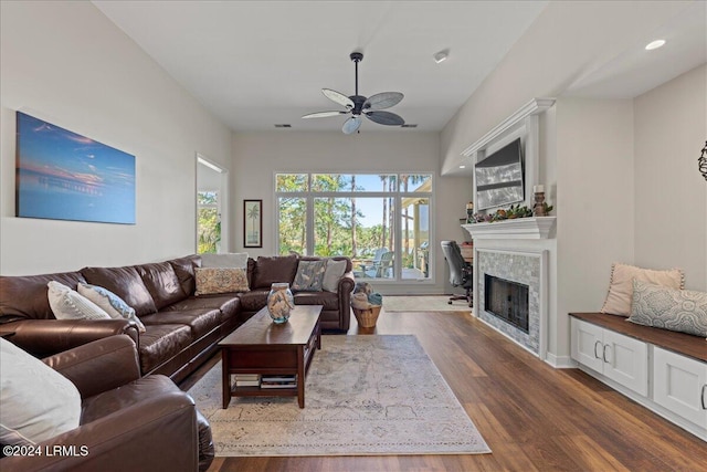 living room with a tiled fireplace, wood-type flooring, and ceiling fan