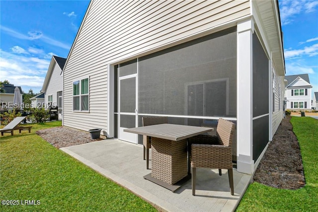rear view of house featuring a patio area, a sunroom, and a lawn