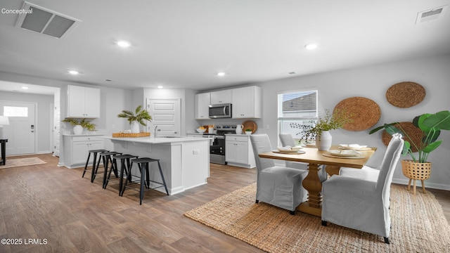 1444 Sanctum St, Ridgeland, SC 29936 - kitchen with stainless steel appliances, a breakfast bar area, light wood-style flooring, a center island with sink, and white cabinets