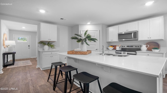 1444 Sanctum St, Ridgeland, SC 29936 - kitchen with appliances with stainless steel finishes, a sink, dark wood-type flooring, a kitchen breakfast bar, and white cabinetry