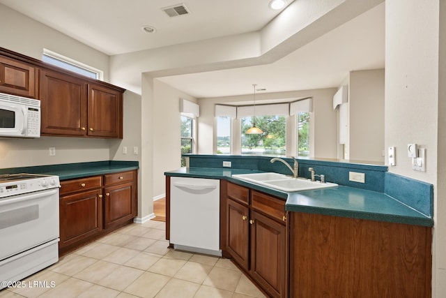 7 Fenwick Dr, Bluffton, SC 29909 - kitchen featuring white appliances, a sink, dark countertops, light tile patterned floors, and a peninsula