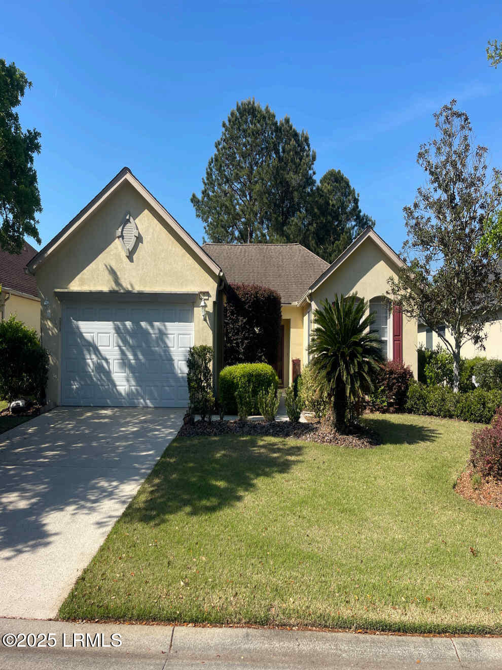 single story home featuring stucco siding, a garage, a front yard, and concrete driveway