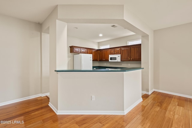 7 Fenwick Dr, Bluffton, SC 29909 - kitchen with white appliances, light wood-style flooring, baseboards, a peninsula, and dark countertops